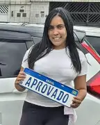 Beatriz Alves segurando a placa de aprovado ao lado do carro de aula da FF Santos