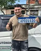 Murilo Aparecido segurando a placa de aprovado ao lado do carro de aula da FF Santos